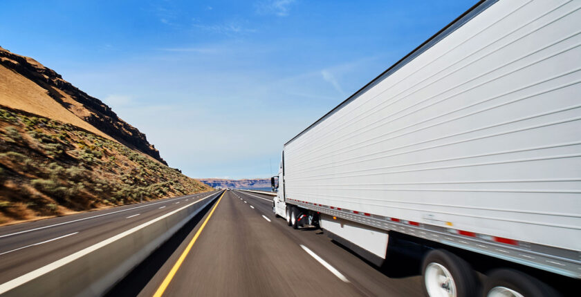 Large white tractor trailer moving down highway with motion blur