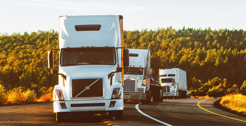 Three white trucks on the road