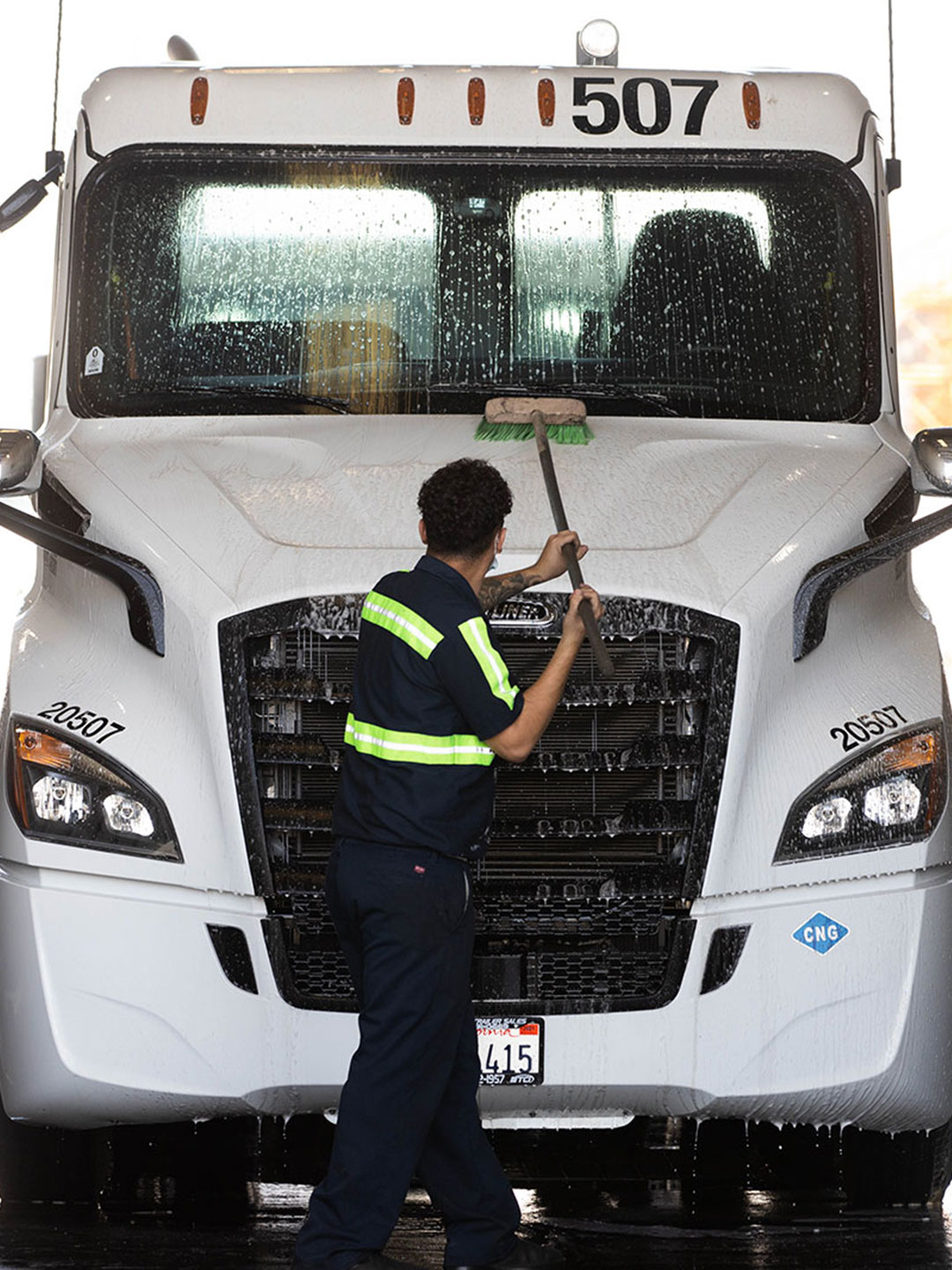 Technician cleaning front hood of Semi cab