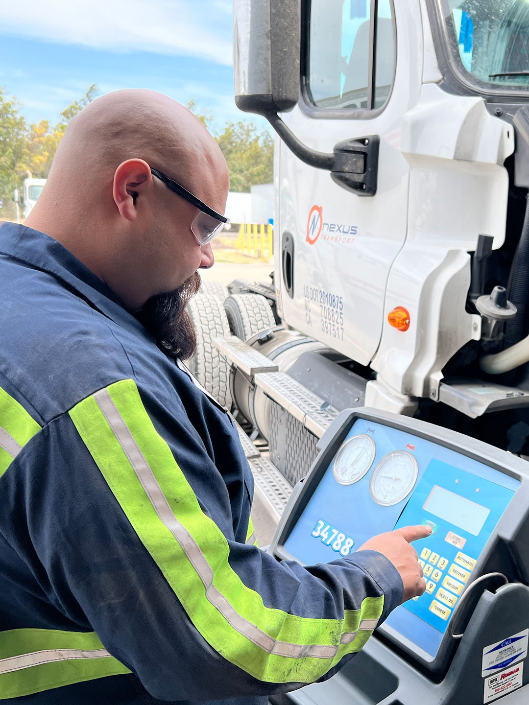 Technician working on computer by an open semi engine