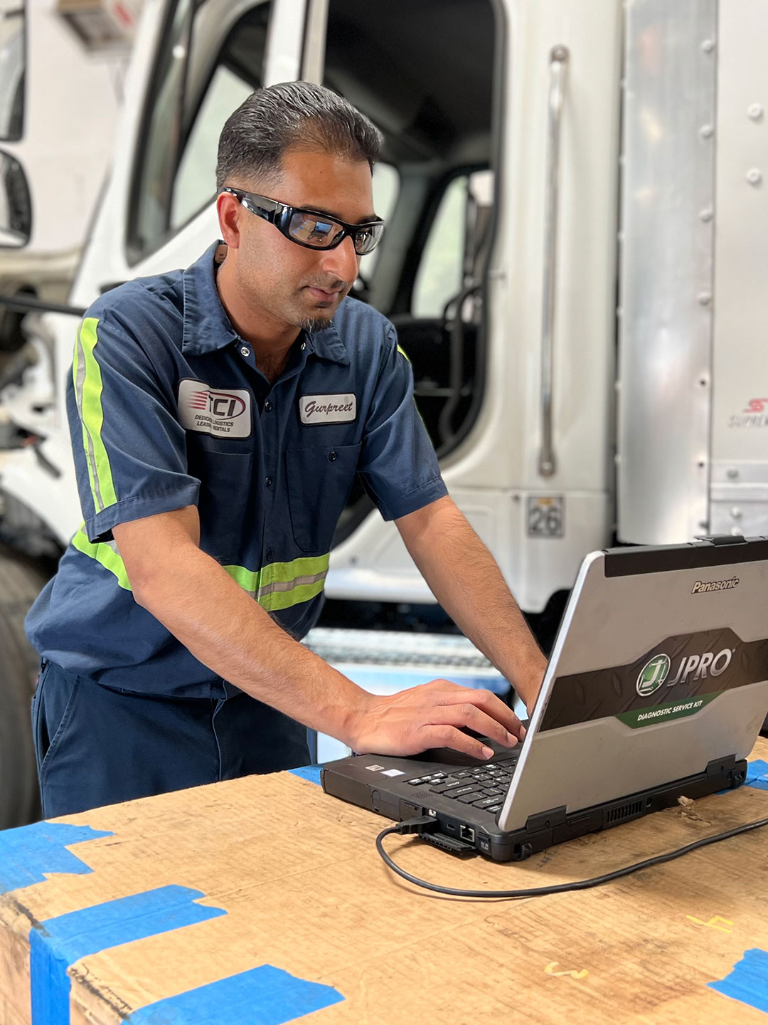 Technician on computer next to large truck