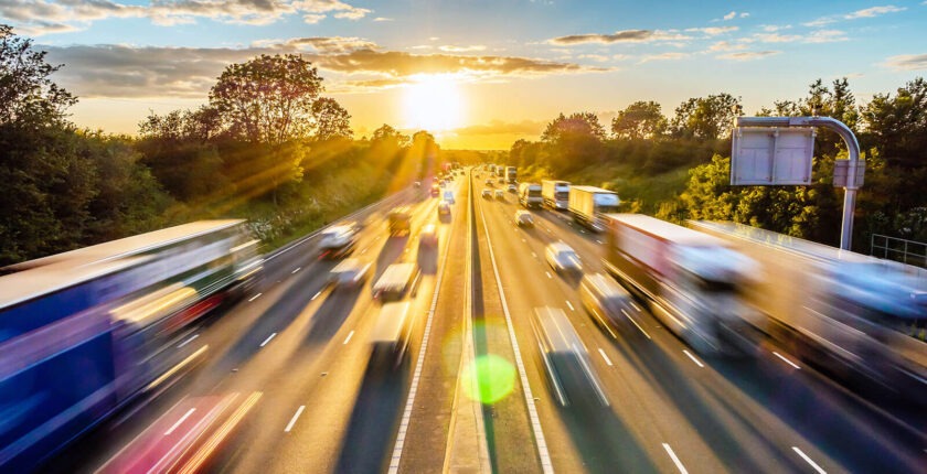 Aerial view of busy highway at sunset with traffic motion blur.