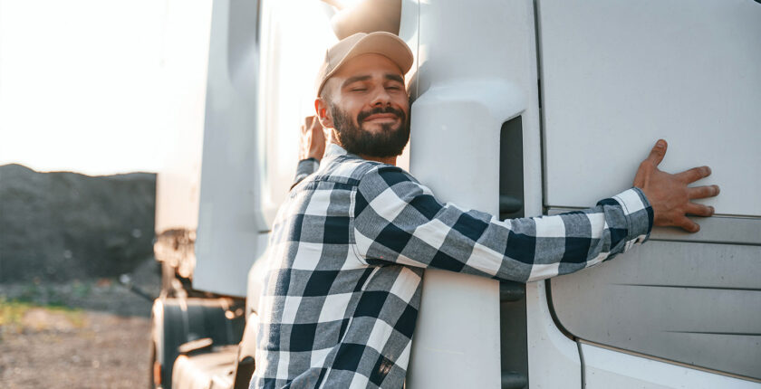 Truck driver embracing the side of his white tractor trailer