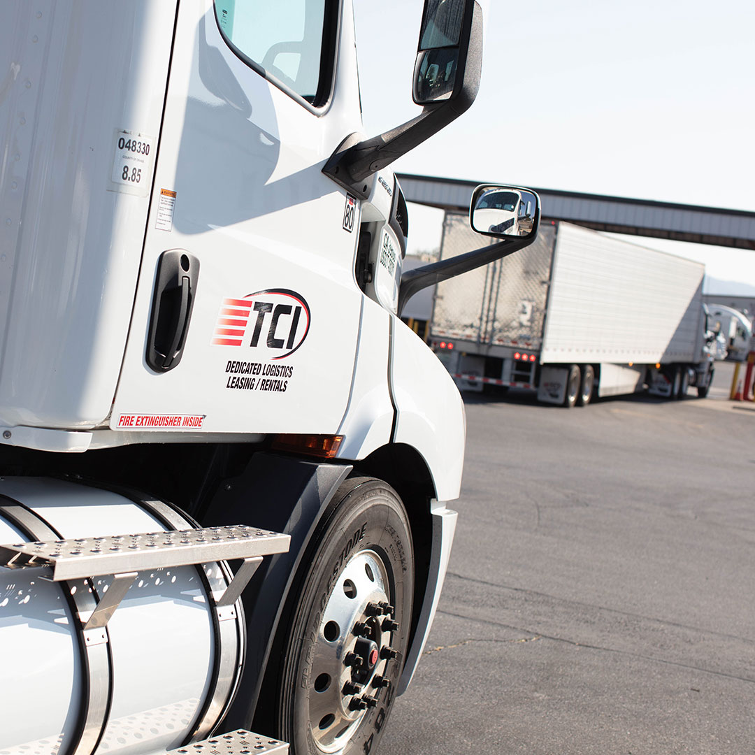 White semi cab with logo centered on door pulling into TCI lot