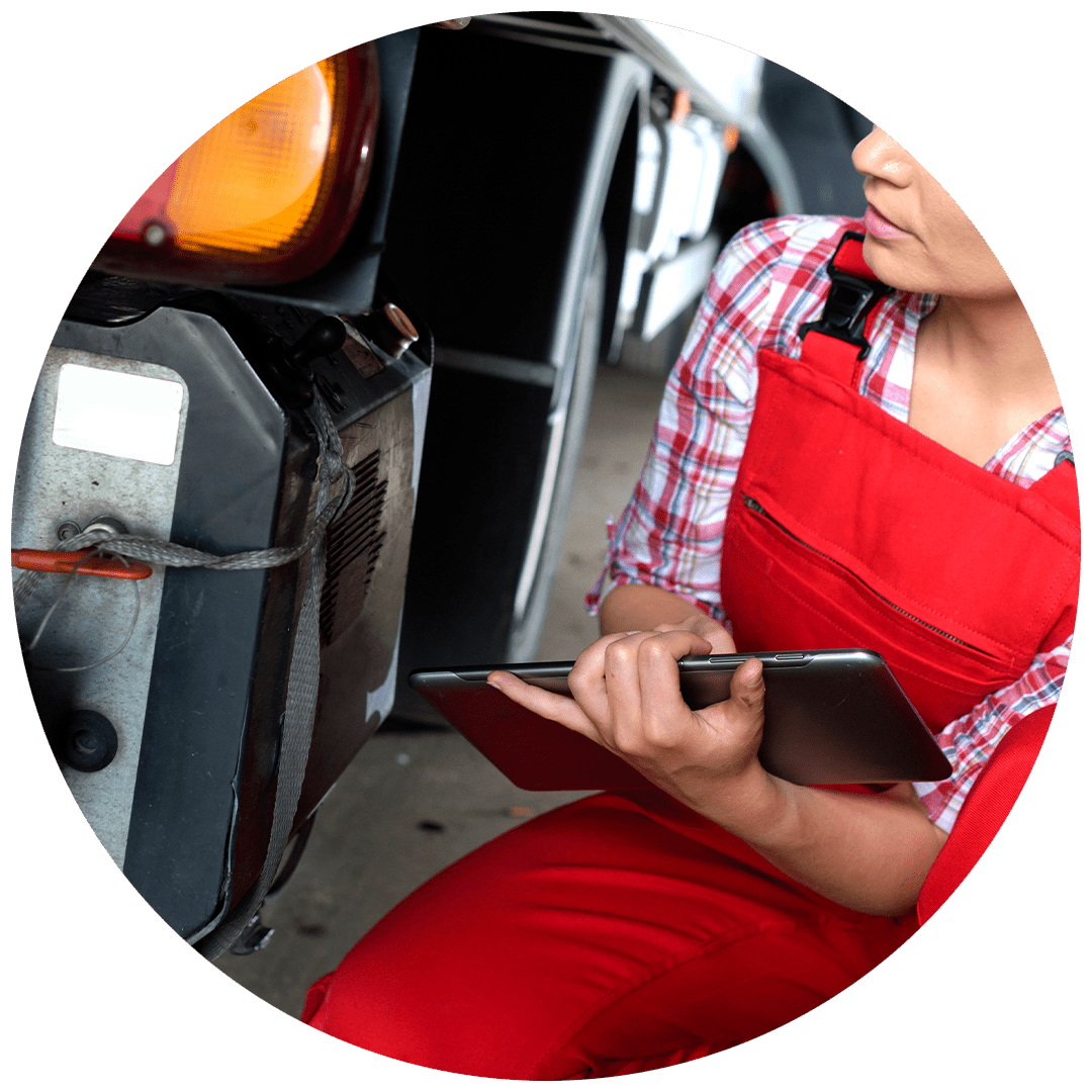 Close-up of woman in red overalls inspecting the lower side of a truck