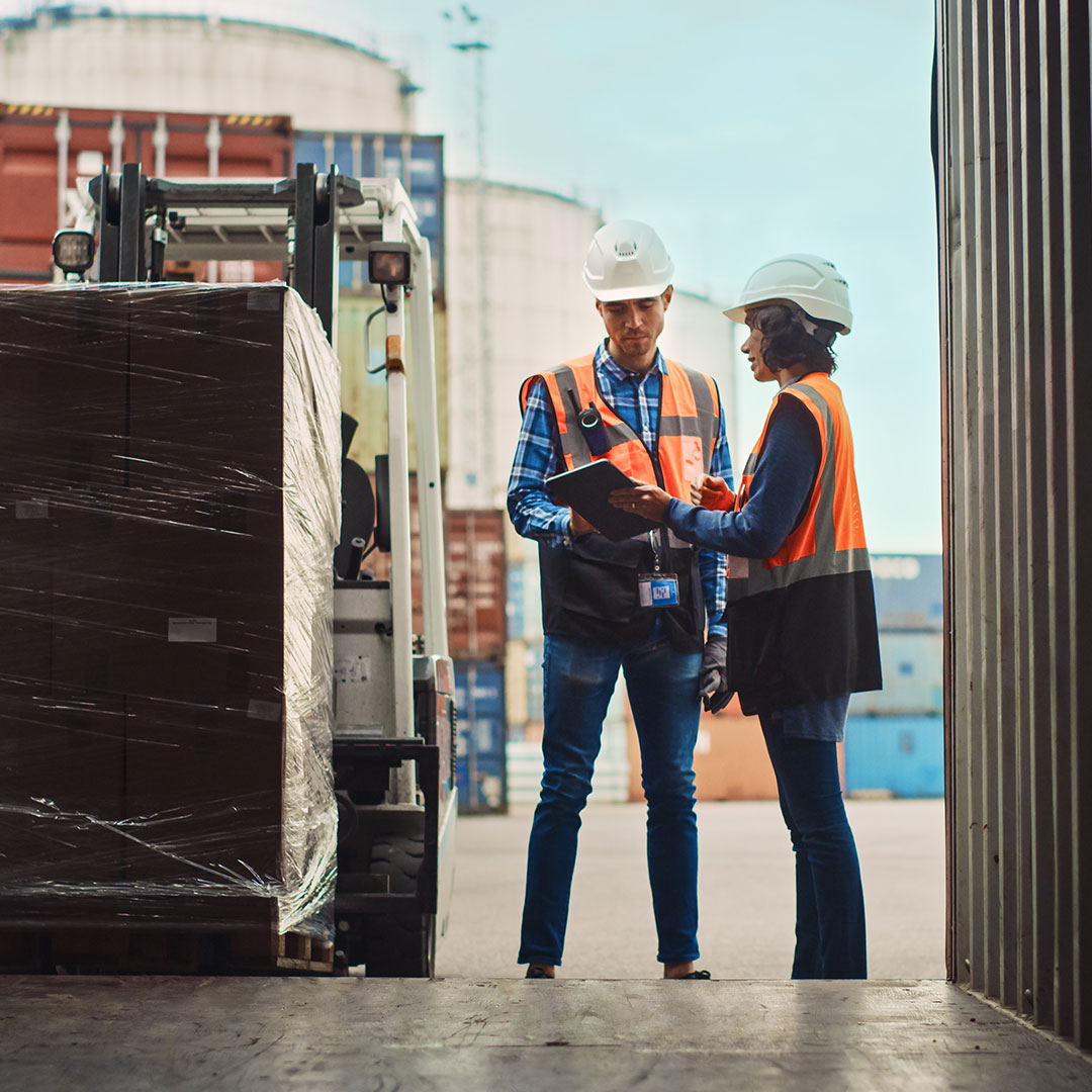 Man and woman in hard hats reviewing documents at loading dock